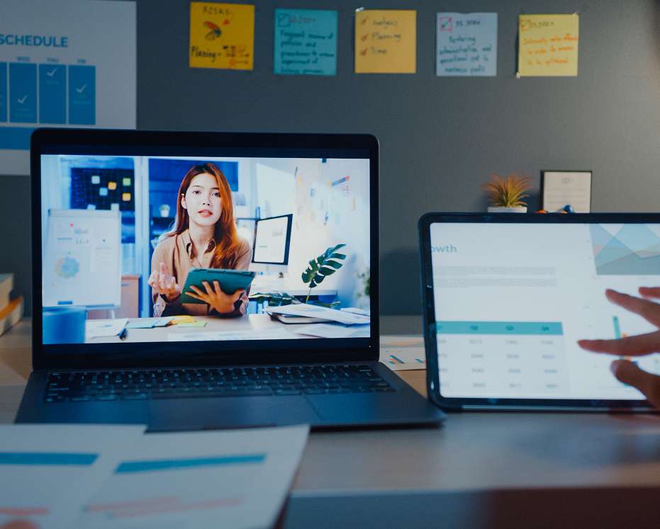 Laptop displaying an online video lesson, alongside a tablet showing learning data on a desk.