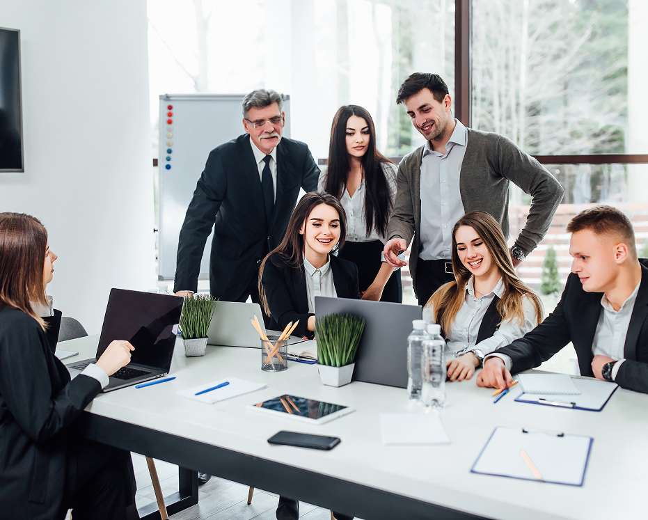 Office team discussing project reports during a meeting showcasing time and attendance solutions by a software solutions company.