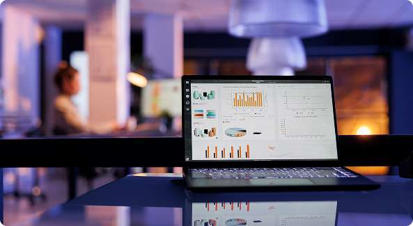 Laptop displaying analytics dashboard and charts in a modern office environment, representing the interface of the best CRM software.