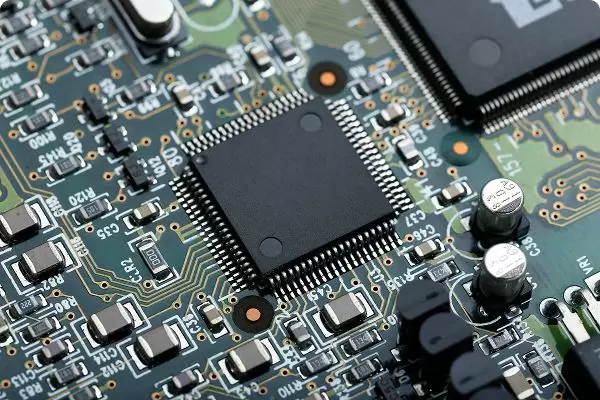Close-up of a printed circuit board with a central microchip and electronic components, representing embedded systems technology.
